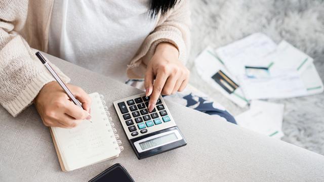 woman writing and using calculator